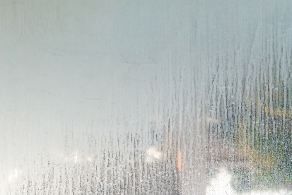 Un vetro della doccia sporco di incrostazioni di calcare